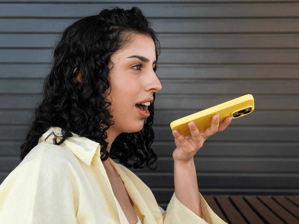 Person speaking into a yellow smartphone.