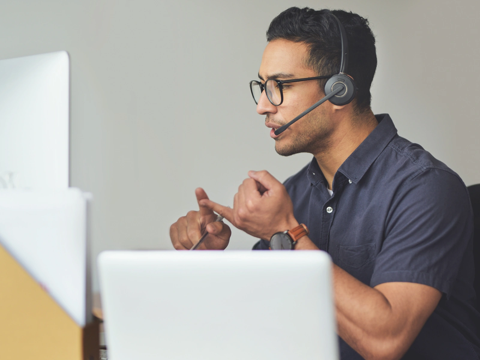 Man wearing a headset and glasses, sitting at a desk in front of a computer