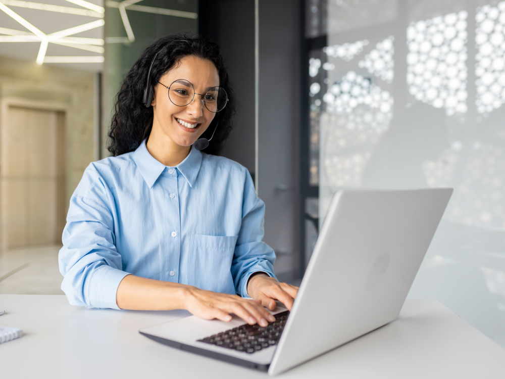 Woman smiling while working on laptop.